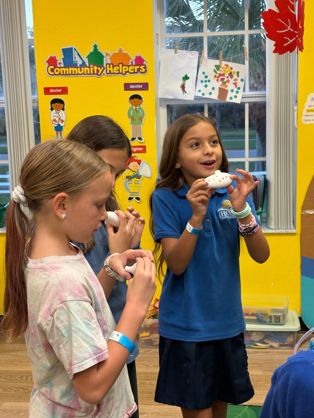 Students try out their white 3D-printed ocarinas.